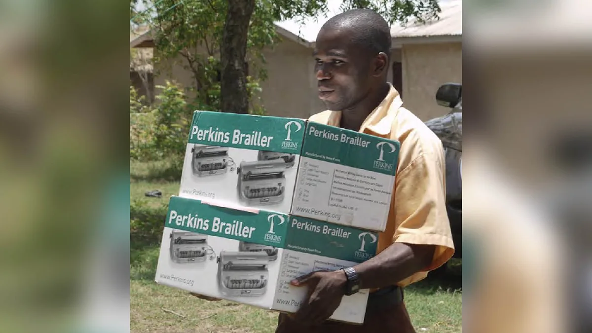 A man carrying two boxed Perkins Braillers.
